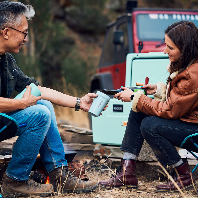 Kodiak 350 Sip Cup Sky Blue 350ml Stainless Steel Insulated Travel Cup shared outdoors by campfire, perfect for camping moments