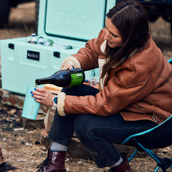 Kodiak 473 Tumbler Seafoam 473ml Insulated Stainless Steel Drinkware, woman pouring drink at outdoor campsite with hard cooler
